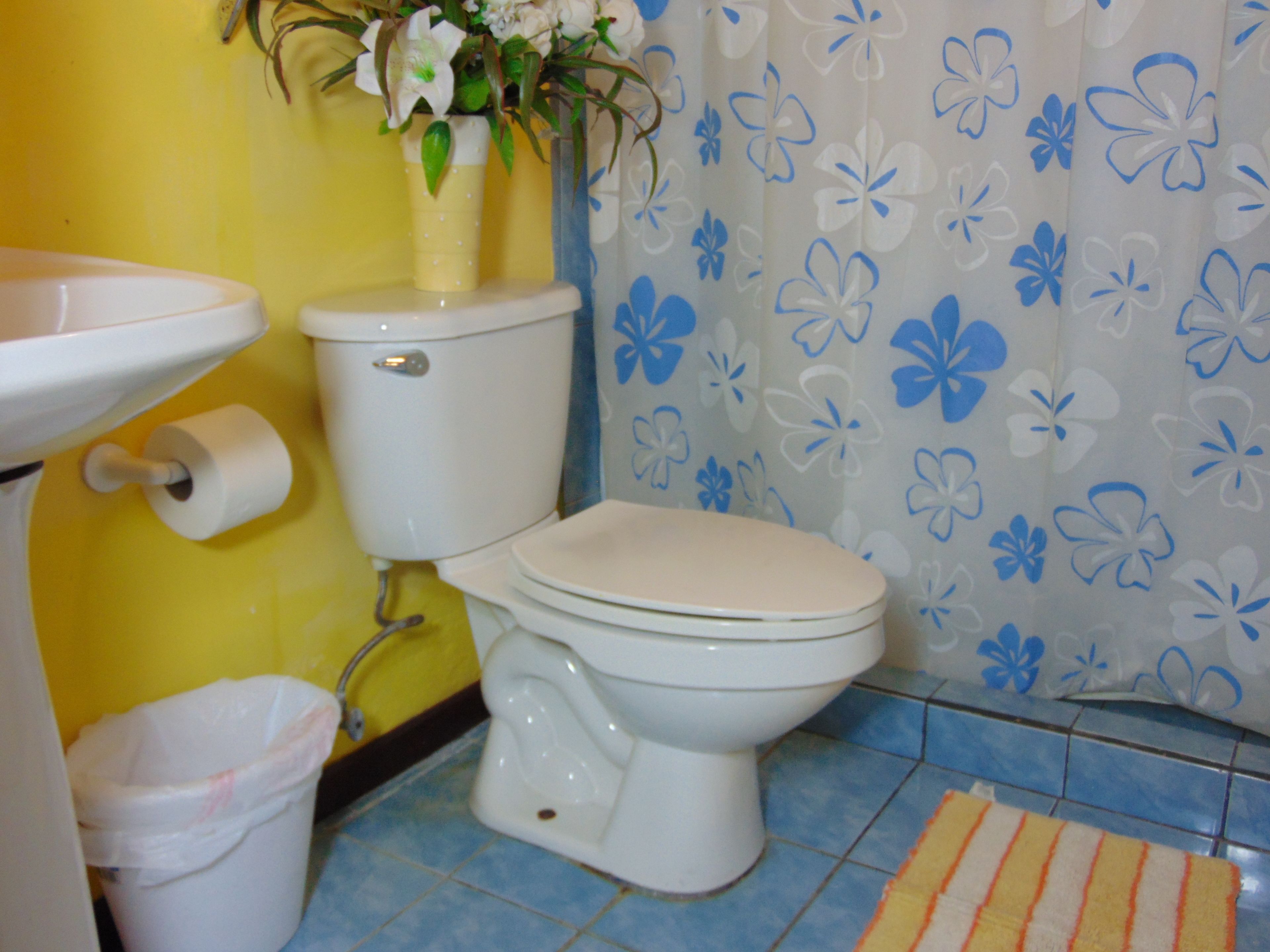A bathroom with a toilet, sink, and trash can.