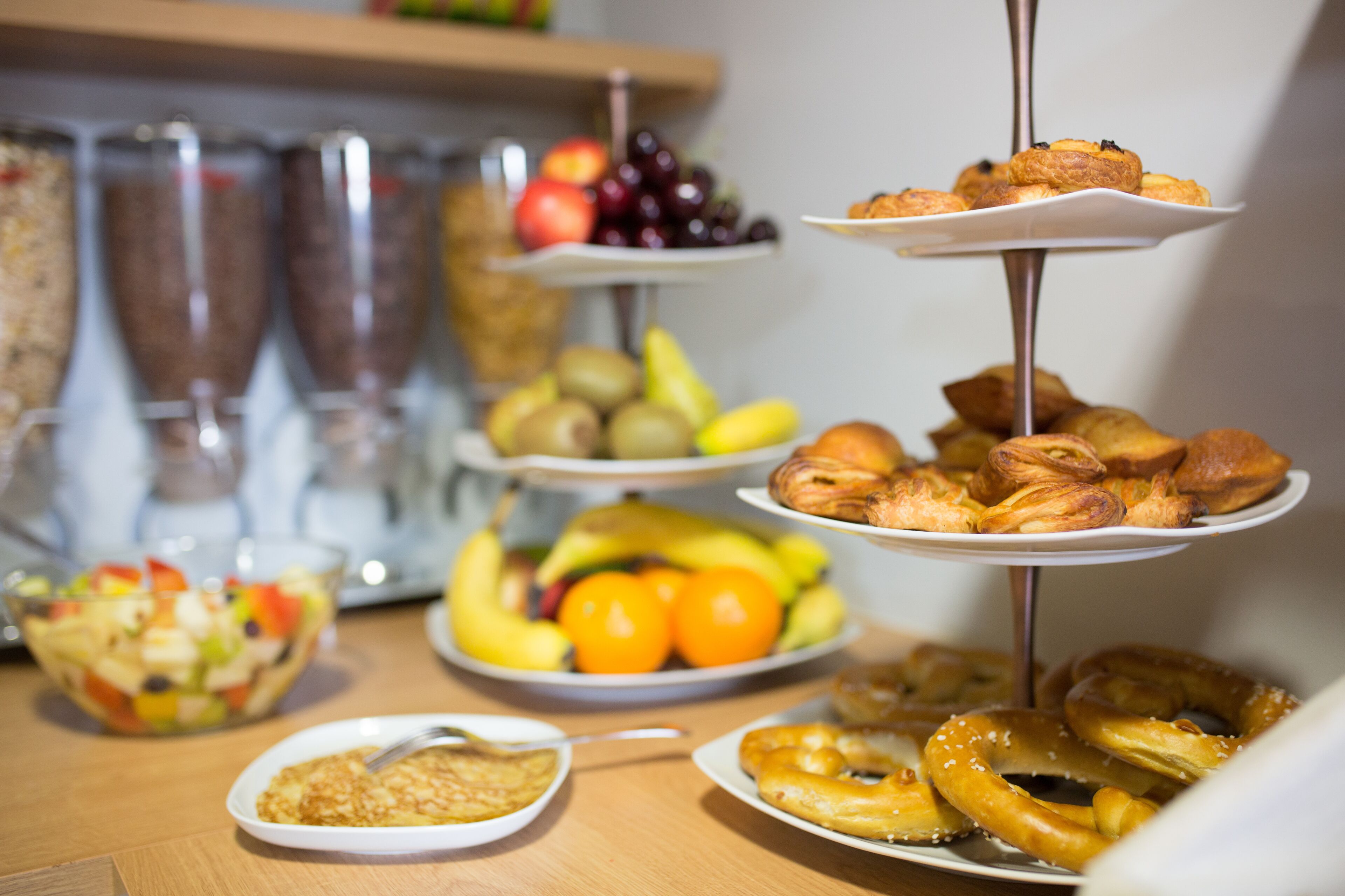 Una mesa de buffet con diversos alimentos, como frutas, pasteles y una ensalada.