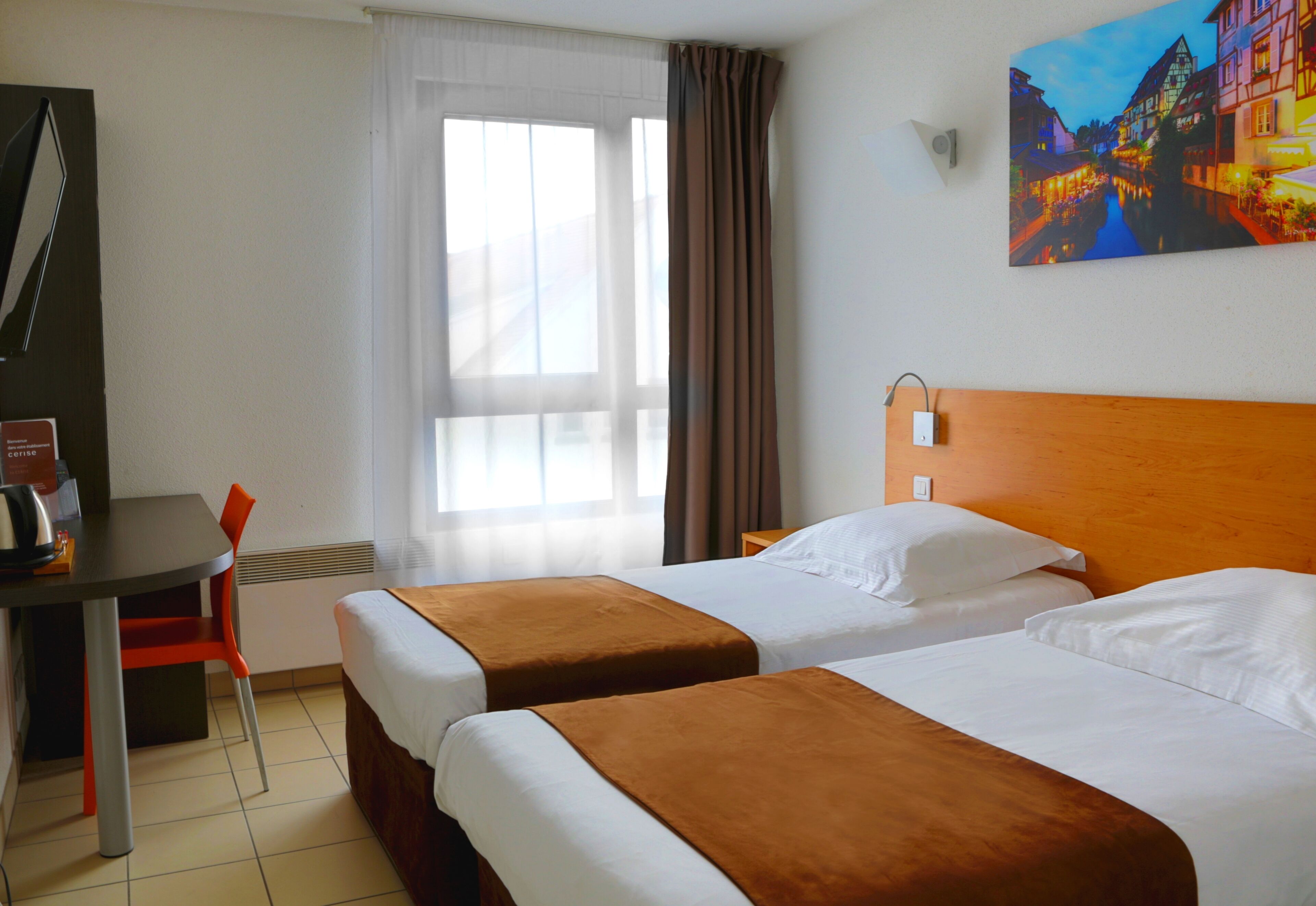 A hotel room with two beds, a desk, a chair, and a painting on the wall.