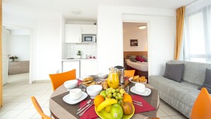 A dining area with a breakfast setup including fruits, bread, and beverages. - Cerise Strasbourg (Strasbourg)