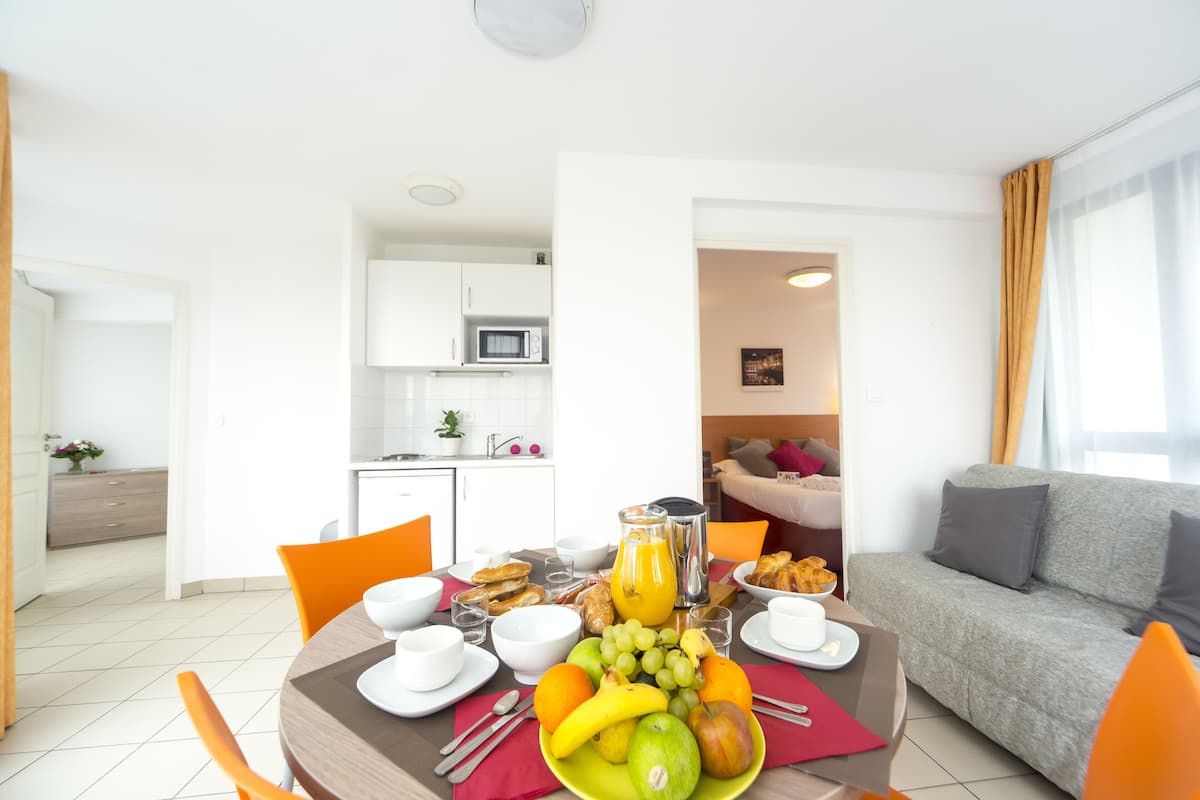 Un espace repas aménagé pour le petit-déjeuner, avec des fruits, du pain et des boissons.