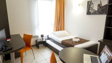 Habitació d'hotel amb un llit, un escriptori amb un ordinador portàtil, una cadira i una televisió.