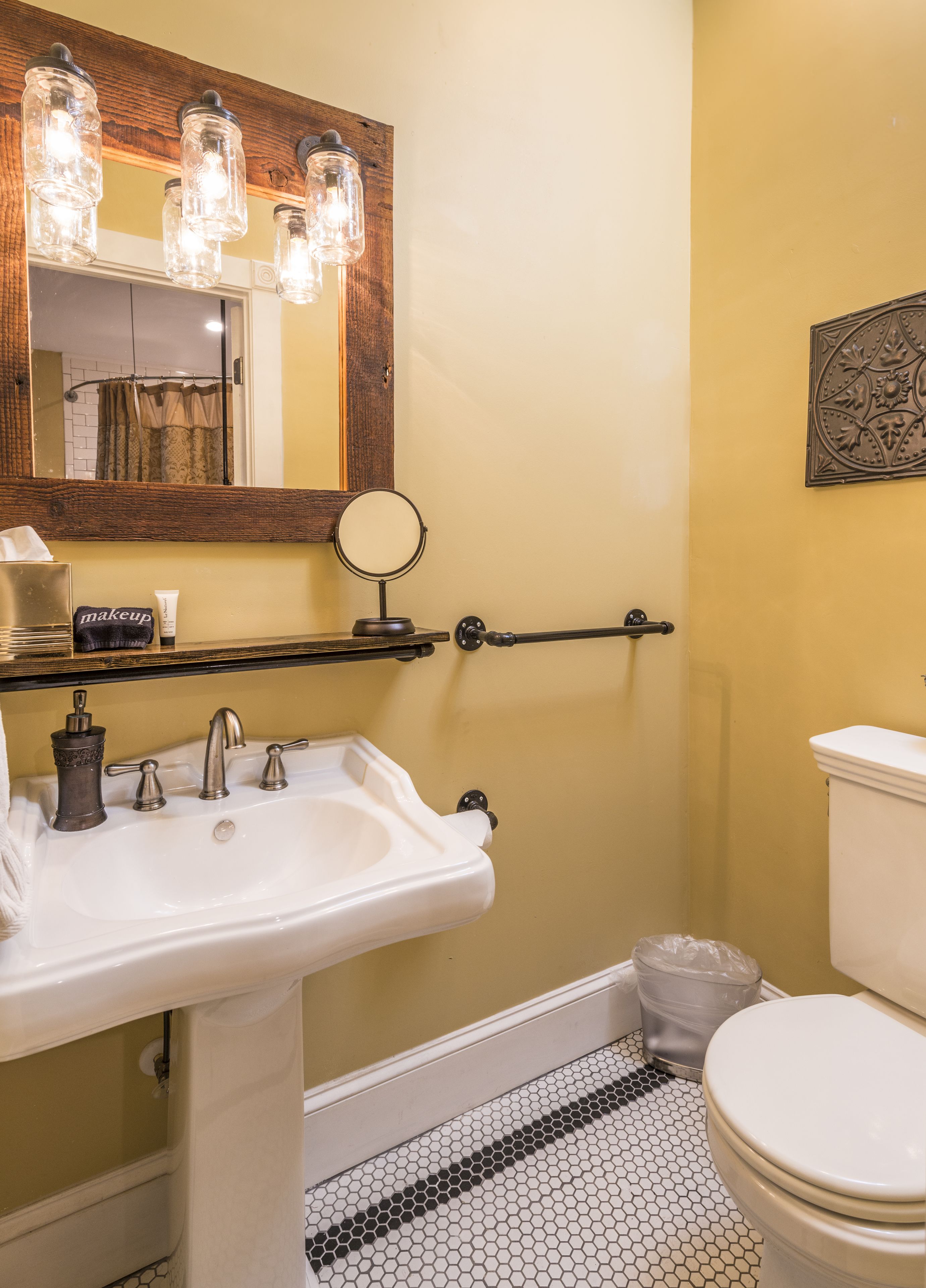 Un baño con lavamanos blanco, un espejo con iluminación, inodoro y zona de ducha.