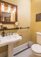 Un baño con lavamanos blanco, un espejo con iluminación, inodoro y zona de ducha.
