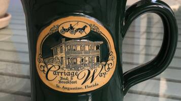 A dark green mug with a vintage design, featuring a horse-drawn carriage and a building illustration, labeled "Carriage Way Bed & Breakfast St. Augustine, Florida."