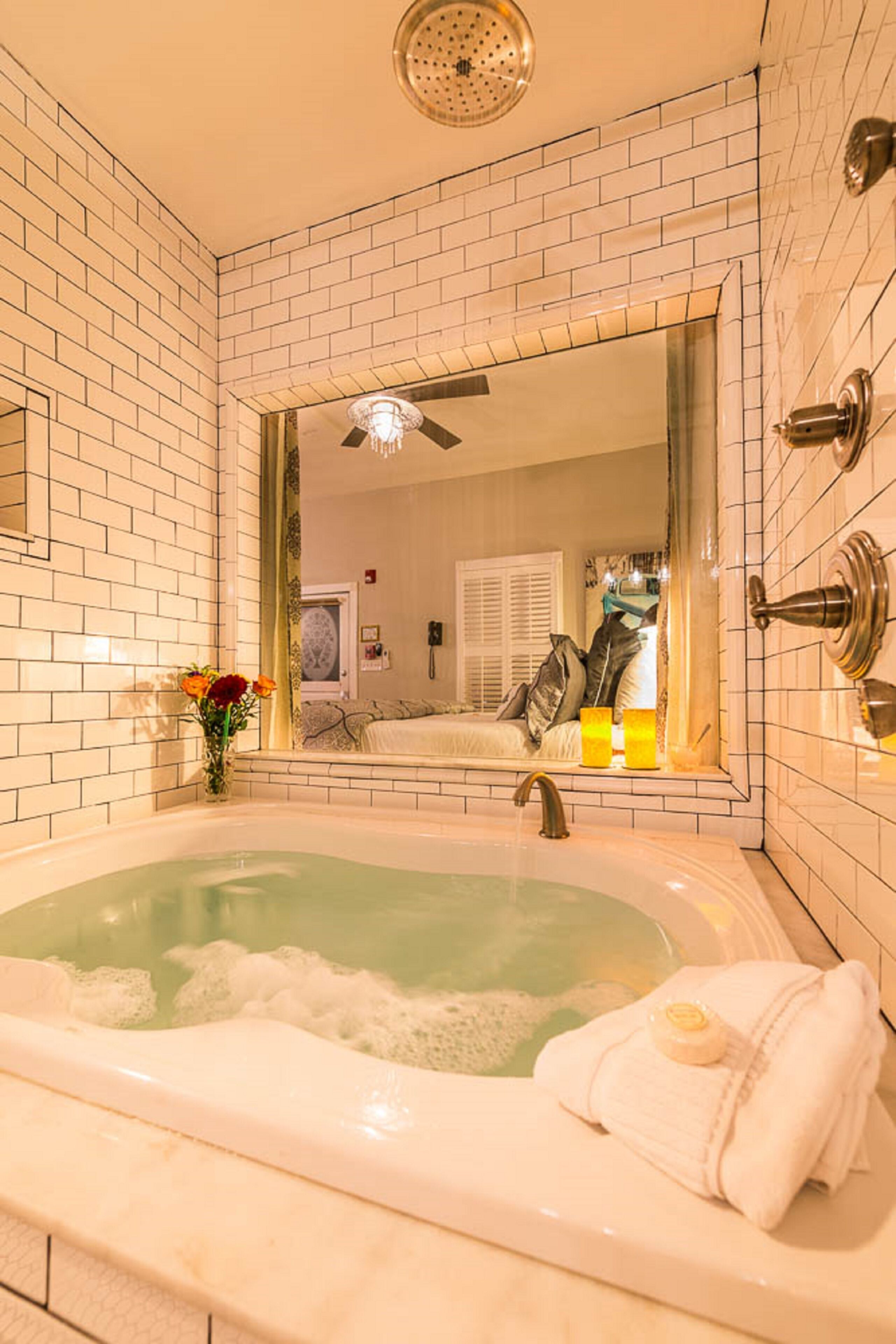 A bathroom with a bathtub, a mirror, and a shower.
