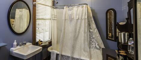 A bathroom with a sink, mirror, shower curtain, and a vanity with a mirror.