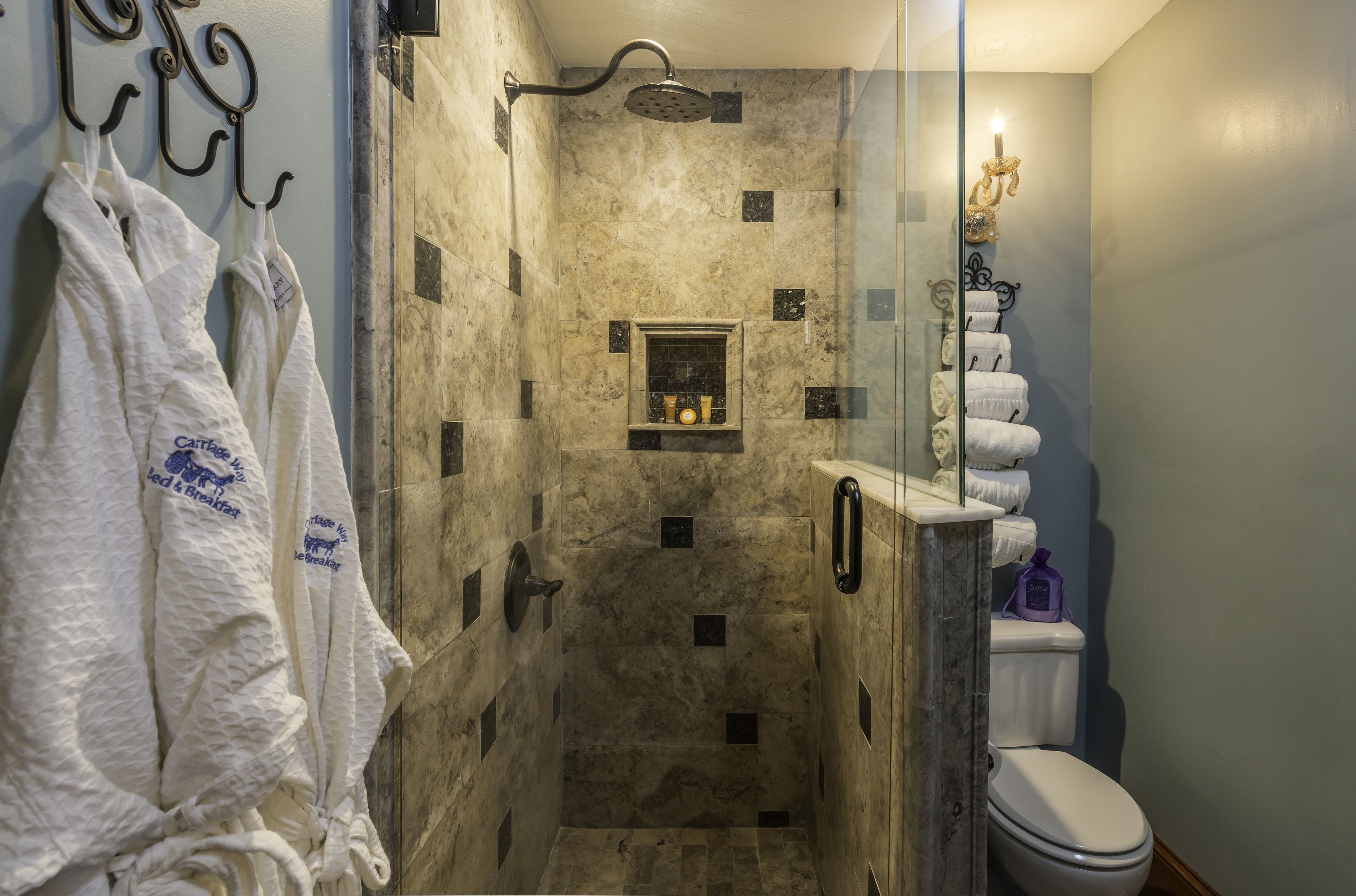Een badkamer met een douche, toilet en een douchecabine met glazen wanden.