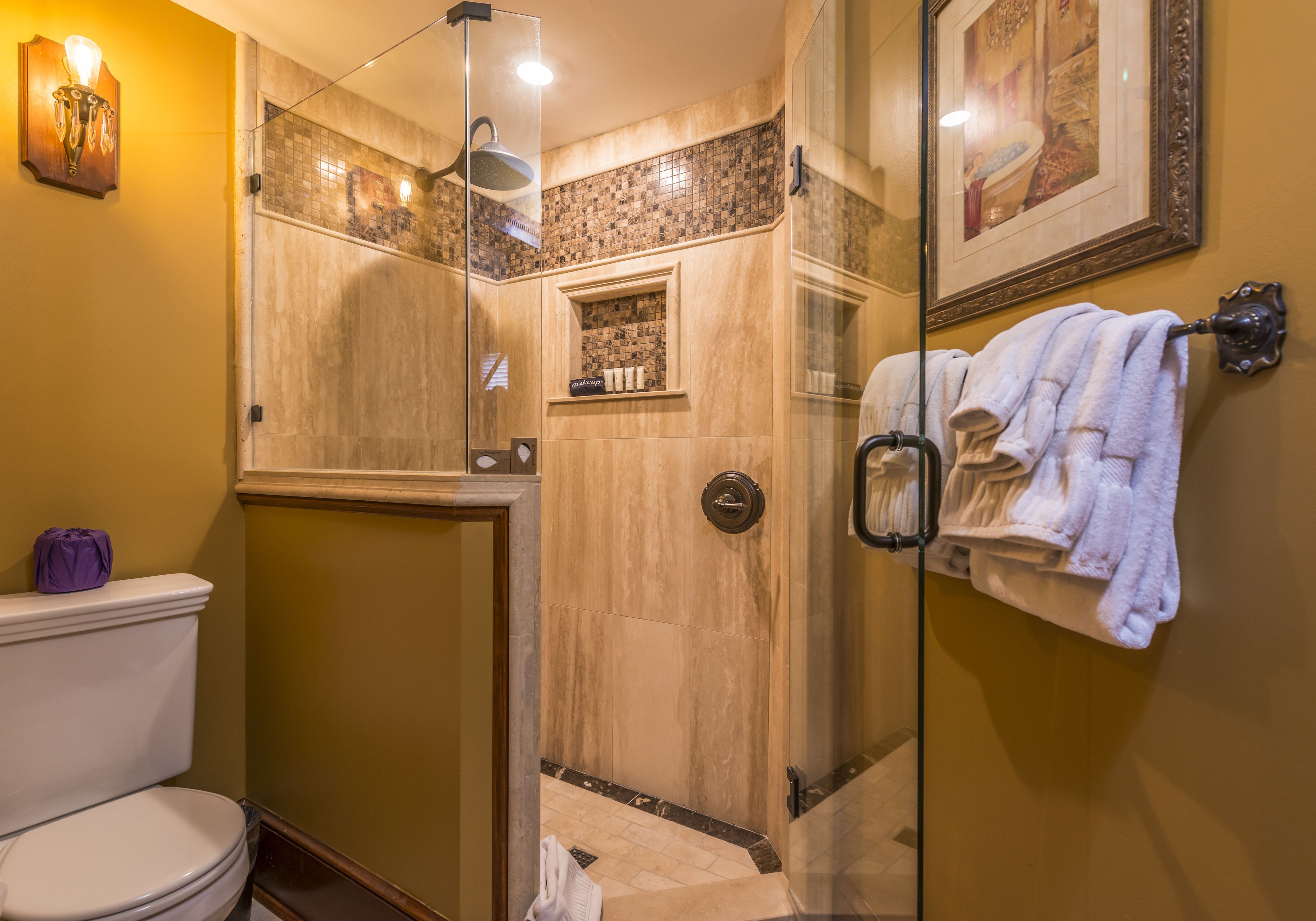 Ein Badezimmer mit Duschkabine, Toilette und Handtuchhalter mit Handtüchern.