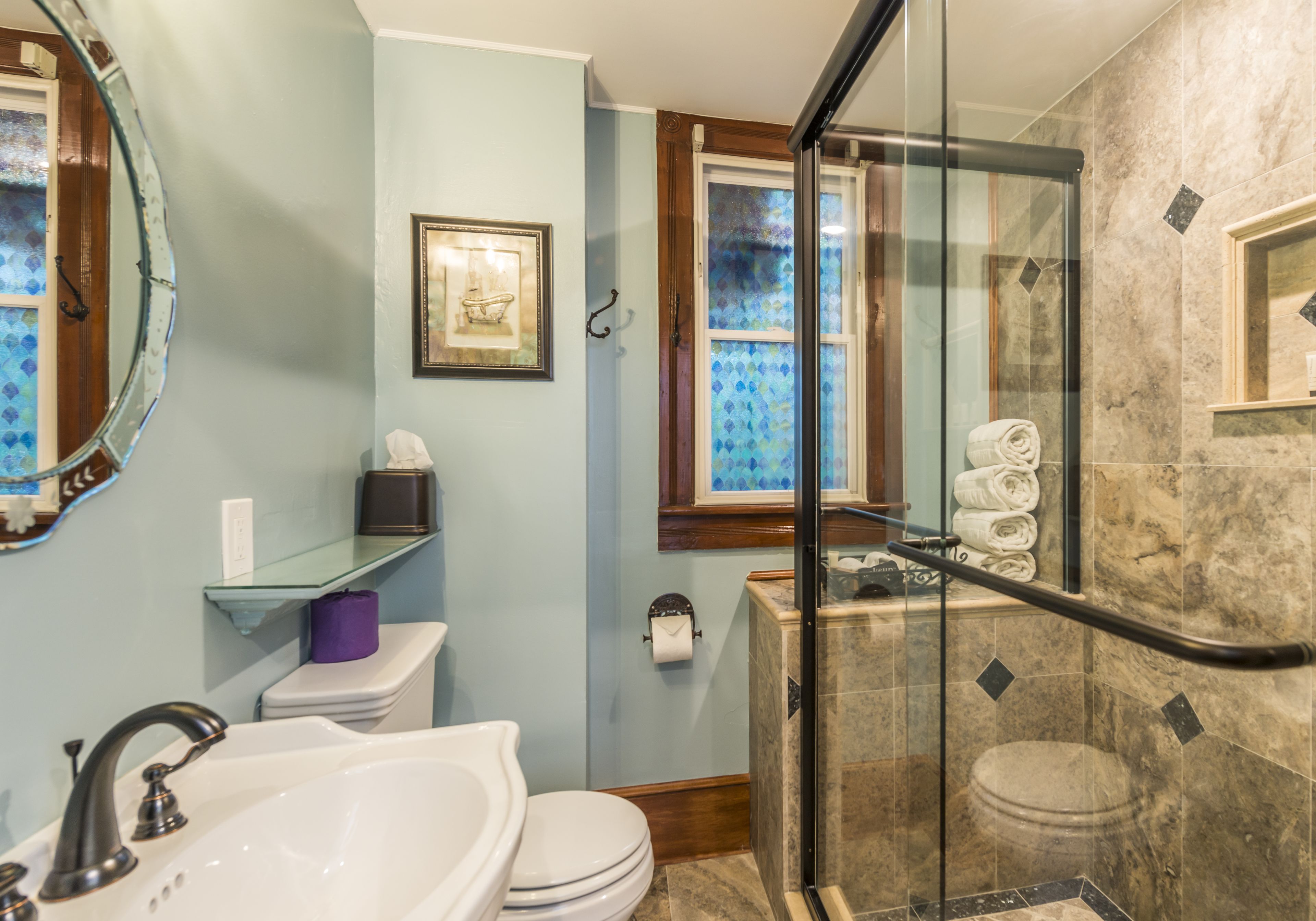 Une salle de bain avec une douche à parois de verre, un lavabo, des toilettes et un tableau encadré au mur.
