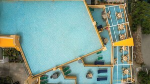 An aerial view of a hotel pool area with multiple lounge areas, sunbeds, and a covered seating area. - Hotel Rivamare (Ischia)