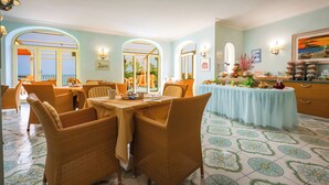 Un comedor con mobiliario de mimbre, una mesa de buffet y vistas a través de un arco.