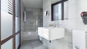 A modern bathroom with a glass shower enclosure, a white sink, and a mirror above it.