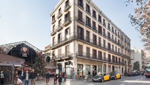 Un edificio de varios pisos con estilo arquitectónico clásico, que cuenta con balcones y una entrada a nivel de calle.