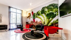 Una sala de estar moderna con un mural grande en la pared, un televisor de pantalla plana y muebles rojo y negro.