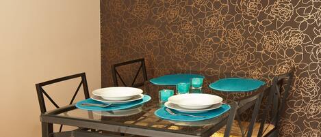 Una mesa de comedor con sillas, una lámpara colgante y un papel tapiz decorado.