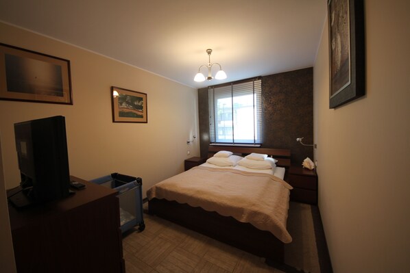 Un dormitorio con cama, televisión, escritorio y ventana.