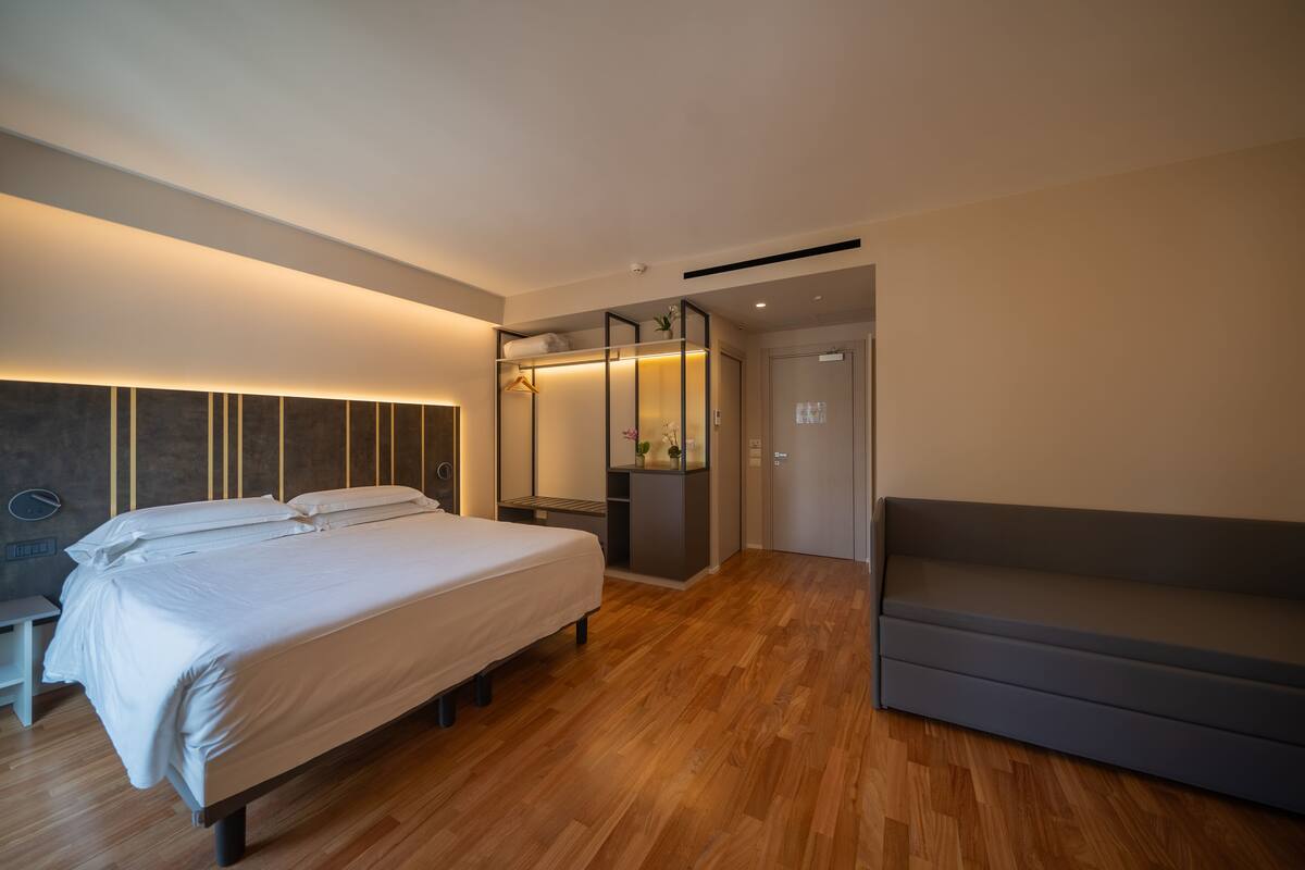 Ein modernes Schlafzimmer mit einem großen Bett, einem Einbauschrank, einer Sitzecke und Holzboden.