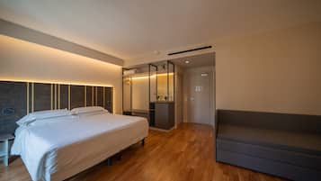 Una camera da letto moderna con un letto grande, un armadio a muro, un angolo salotto e un pavimento in legno.