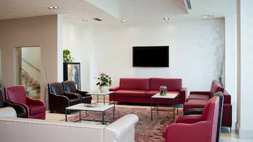 A modern living room with a red sofa, leather armchairs, and a coffee table.