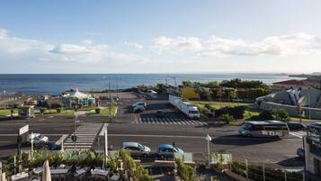 A coastal view with a parking lot, a bus, and a building with a sign.