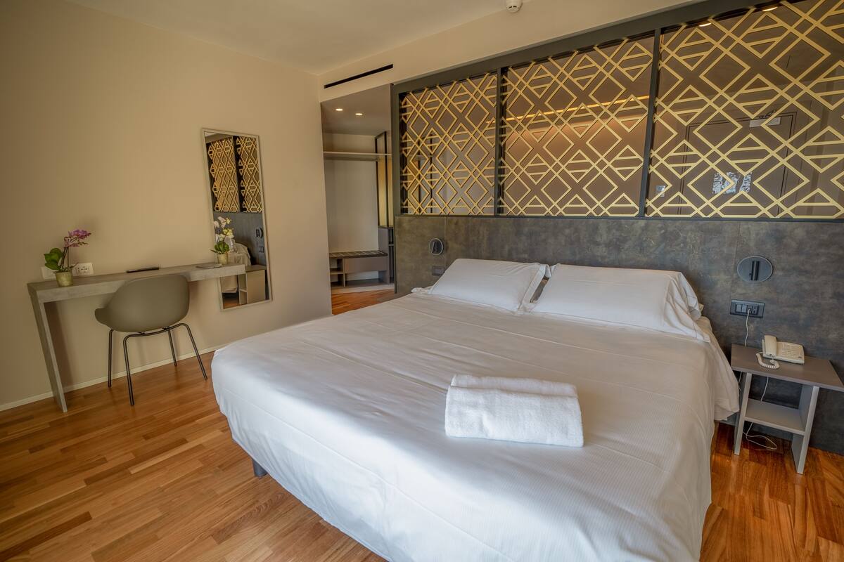 Ein modernes Hotelzimmer mit einem großen Bett, einem Schreibtisch und einem Stuhl.