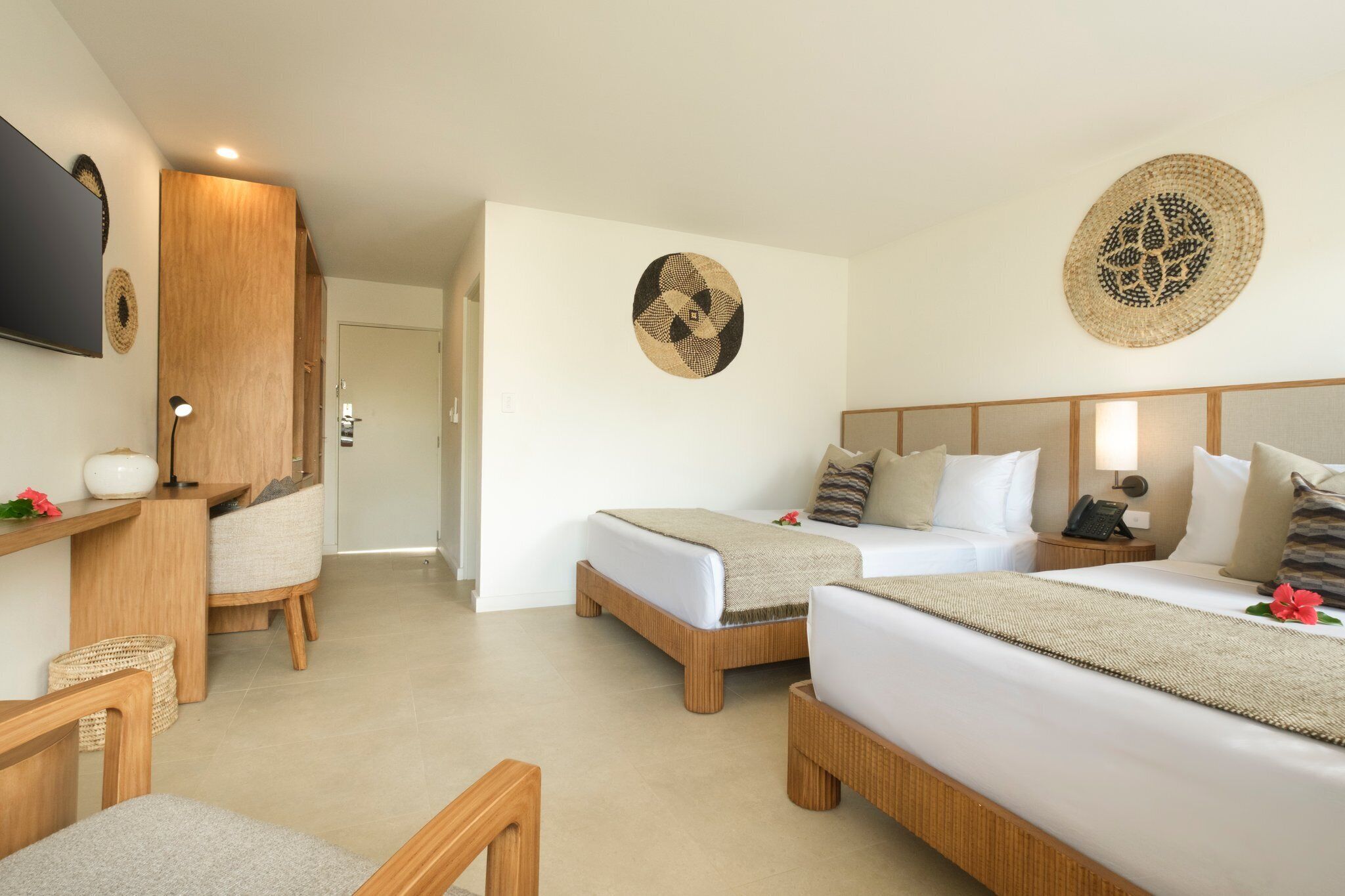 A hotel room with two beds, a TV, a desk, and a chair.