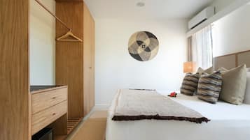 A bedroom with a bed, a wooden wardrobe, a wall-mounted circular artwork, and a bedside lamp.