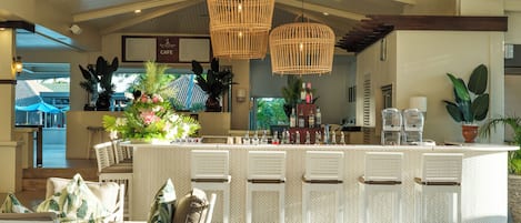 A modern bar area with wicker pendant lights, a central island with bar stools, and a view of the outdoor area.
