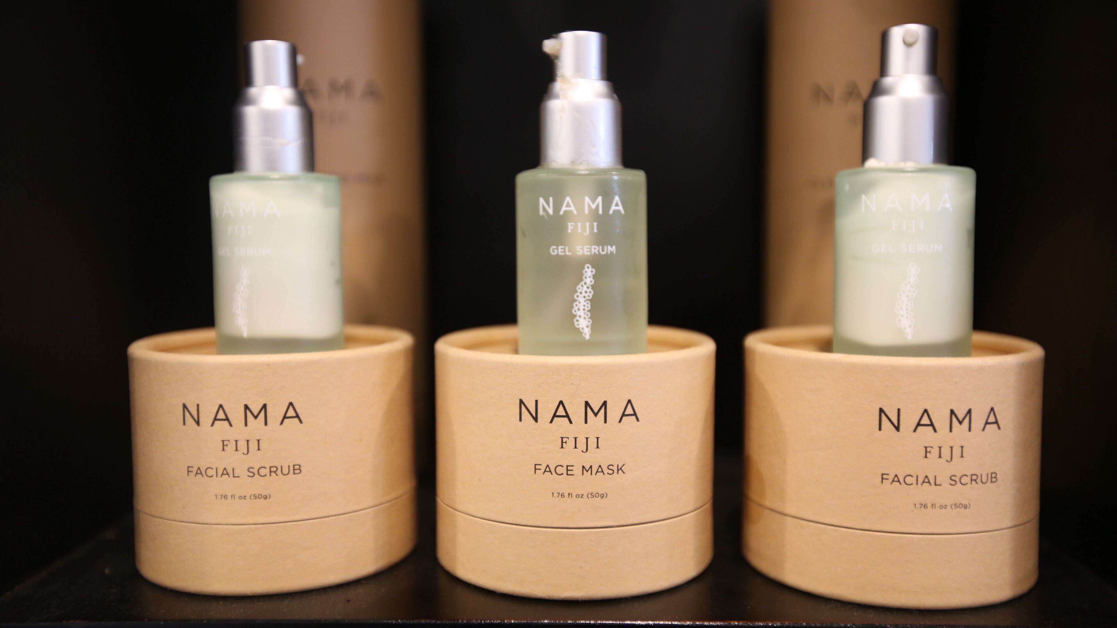 Drei NAMA Fiji Produkte: Gesichtspeeling, Gel-Serum und Gesichtsmaske, jedes in einer beige farbenen Verpackung.