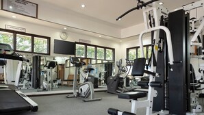 A fitness center with exercise equipment, large windows, and a clock on the wall. - Fiji Gateway Hotel (Nadi)