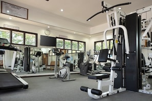 A fitness center with exercise equipment, large windows, and a clock on the wall. - Fiji Gateway Hotel (Nadi)