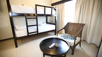 A hotel room with bunk beds, a round table, and a chair.