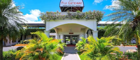 The Fiji Gateway Hotel entrance with a clear pathway, palm trees, and a sign above.
