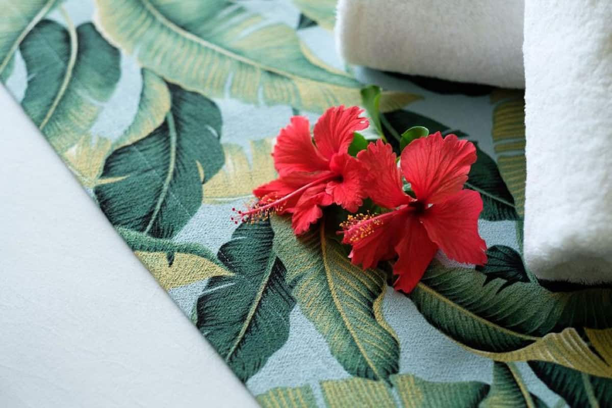 A bed with a floral patterned bedspread and a white towel.
