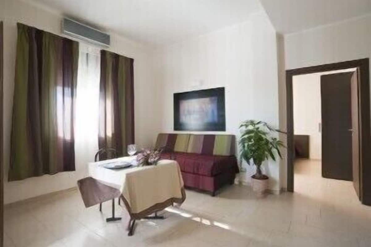 A modern living room with a dining table, a sofa, and a potted plant.