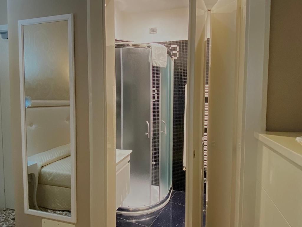 A bathroom with a glass-enclosed shower, a toilet, and a mirror.