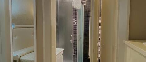 A bathroom with a glass-enclosed shower, a toilet, and a mirror.