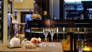 A bar area with a wooden table, two champagne flutes, a bowl of fruit, and a candle. - Hotel Ai Due Principi (Venice)