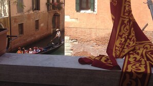 A canal with a gondola, buildings with balconies, and a flag. - Hotel Ai Due Principi (Venice)