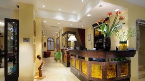 A reception area with a wooden counter, a staircase, and a glass display case. - Hotel Ai Due Principi (Venice)