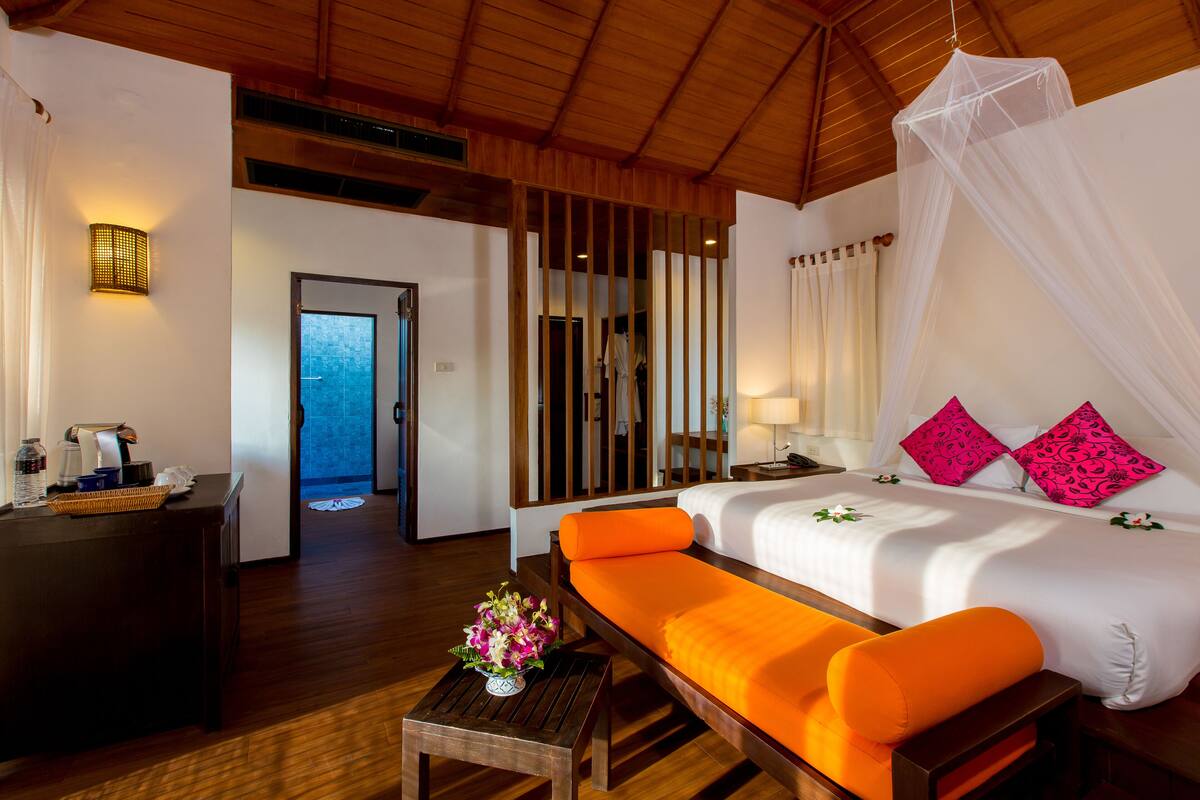Habitación de hotel con cama, sofá, escritorio, lámpara y vistas al exterior.