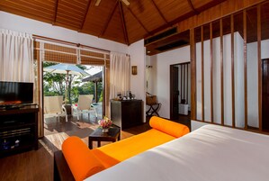 Habitación de hotel con cama, televisor, escritorio y balcón con mobiliario exterior.