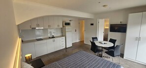 A compact kitchen with a microwave, refrigerator, and a dining area with a table and chairs.