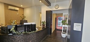 Een receptie met een receptiebalie, een klok, een automaat en een potplant.