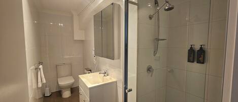A modern bathroom with a toilet, sink, and shower.