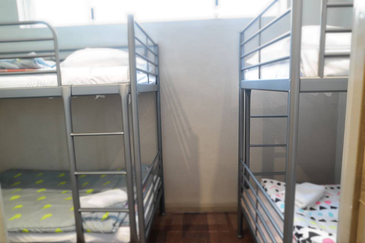 Een slaapkamer met een stapelbed, metalen spijlen en een bed met een dessin.