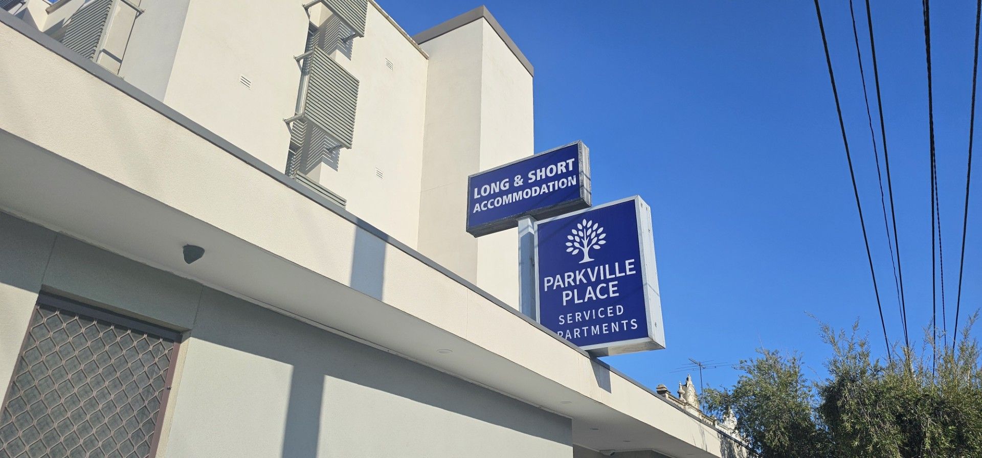 Un immeuble avec une enseigne indiquant « HÉBERGEMENT À LA SEMAINE OU AU MOIS » et « APPARTEMENTS DE LUXE PARKVILLE PLACE ».