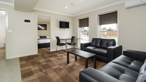 Un salon moderne comprenant un canapé, une table basse et un coin repas avec des chaises et une table.