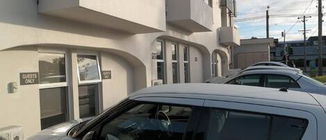 Um carro branco estacionado em frente a um edifício com uma placa na porta que diz 'GUESTS ONLY'.